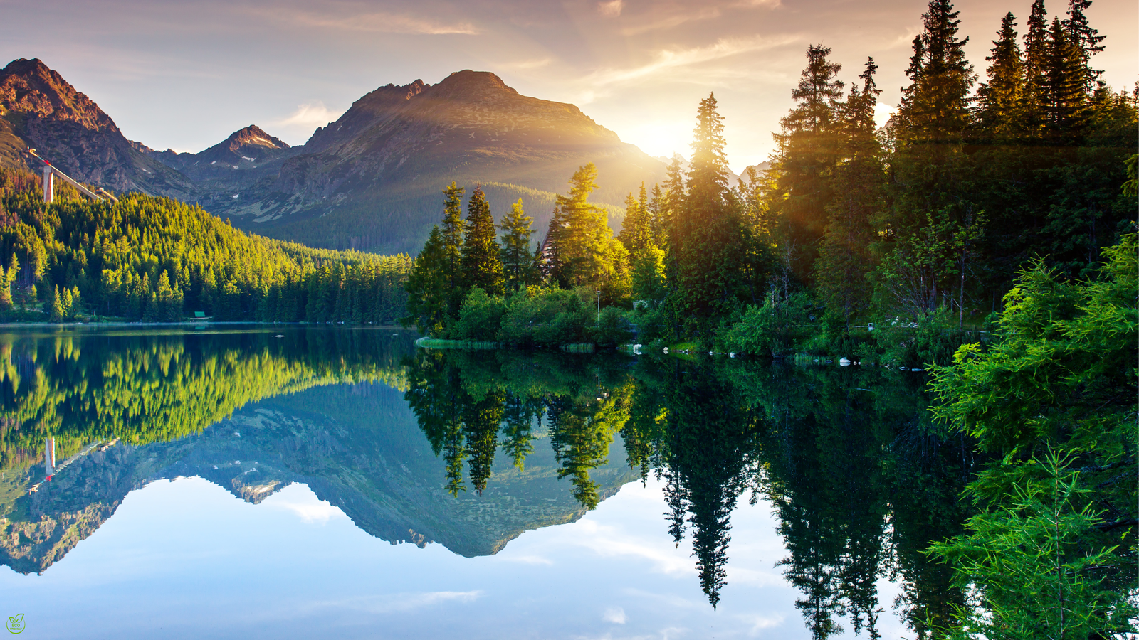Peaceful lake surrounded by green mountains under clear sky — symbol of sustainable ecotourism 2025