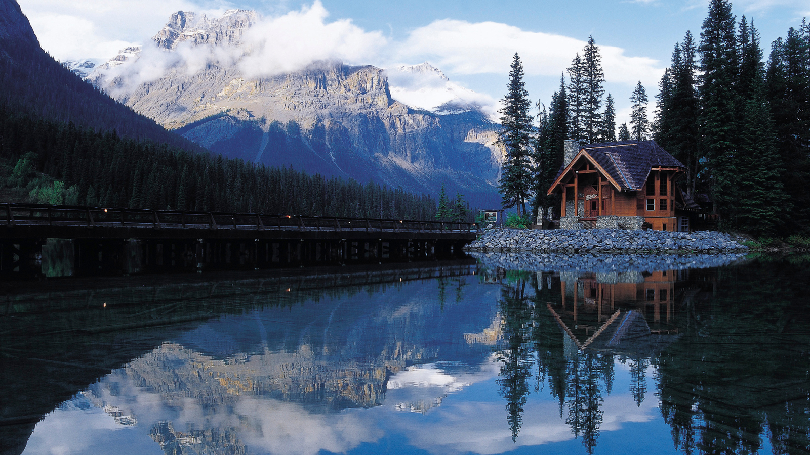 Lakeside cabin in the mountains surrounded by pine trees and mist — a serene setting for quietcations and digital detox retreats in 2025.