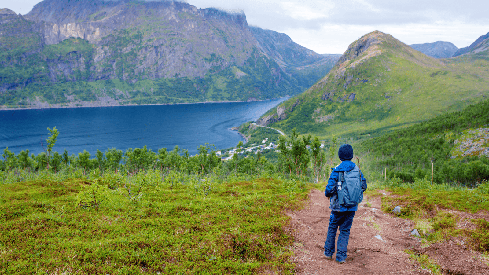 Traveler hiking along a Scandinavian fjord trail — sustainable travel in 2025