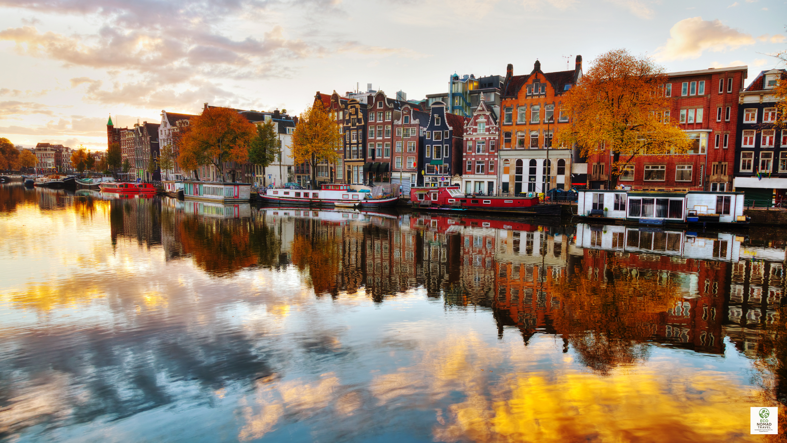Wide view of Amsterdam city and canal with boats and canal houses, illustrating a key stop on a European rail-first flight-free travel itinerary in 2025