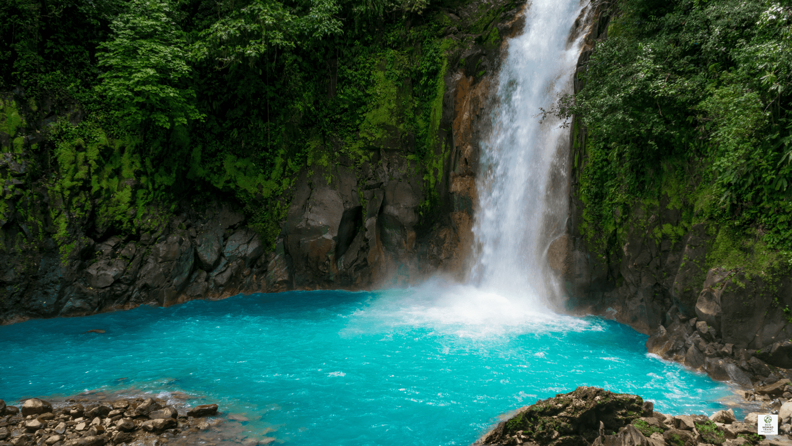 Rio Celeste waterfall in Costa Rica pouring into a blue pool, surrounded by rainforest near eco lodges and farm stays.