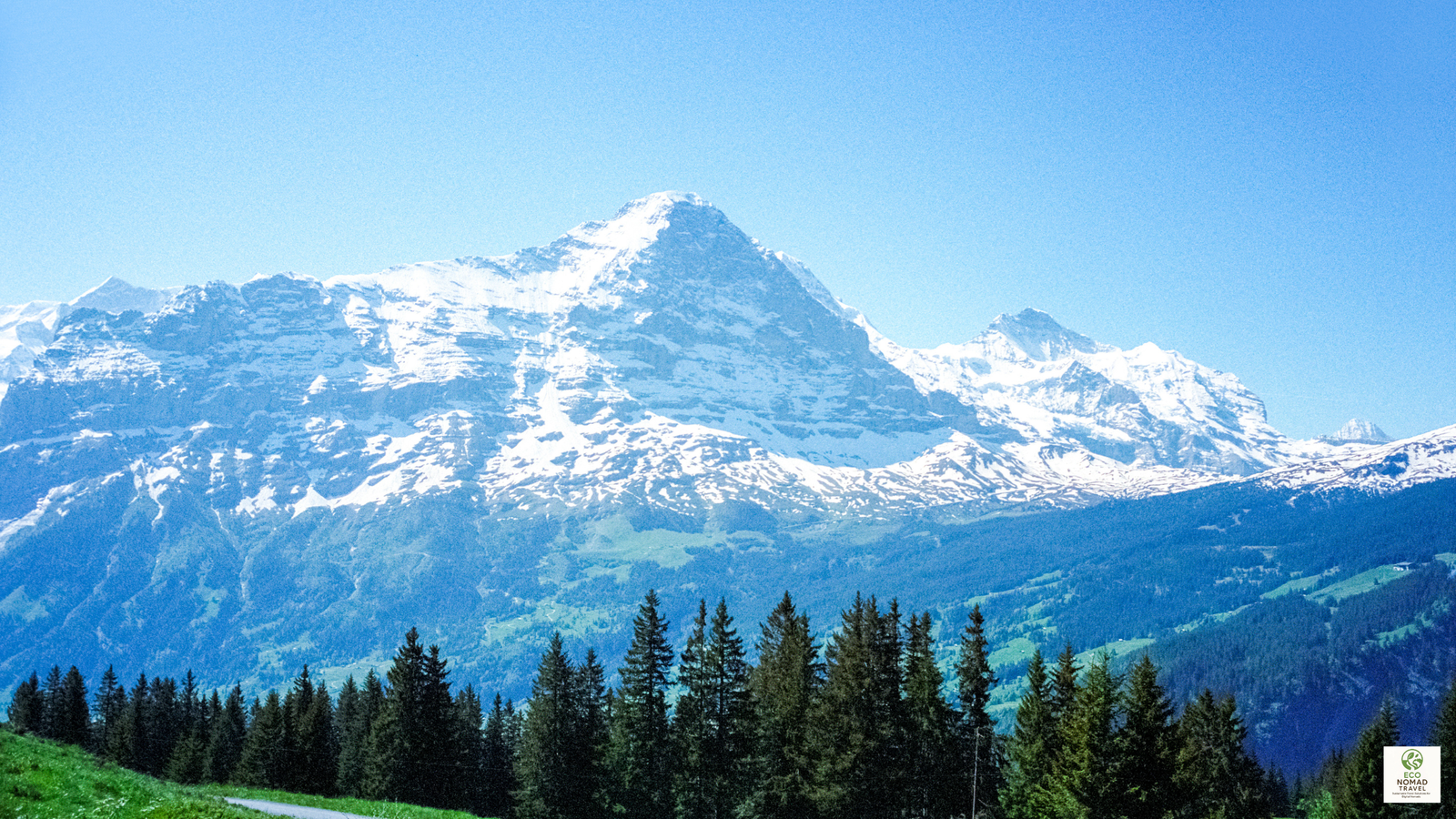 Snow-covered Swiss Alps with cabins and eco pods on a hillside, representing off-grid eco lodging in 2025.