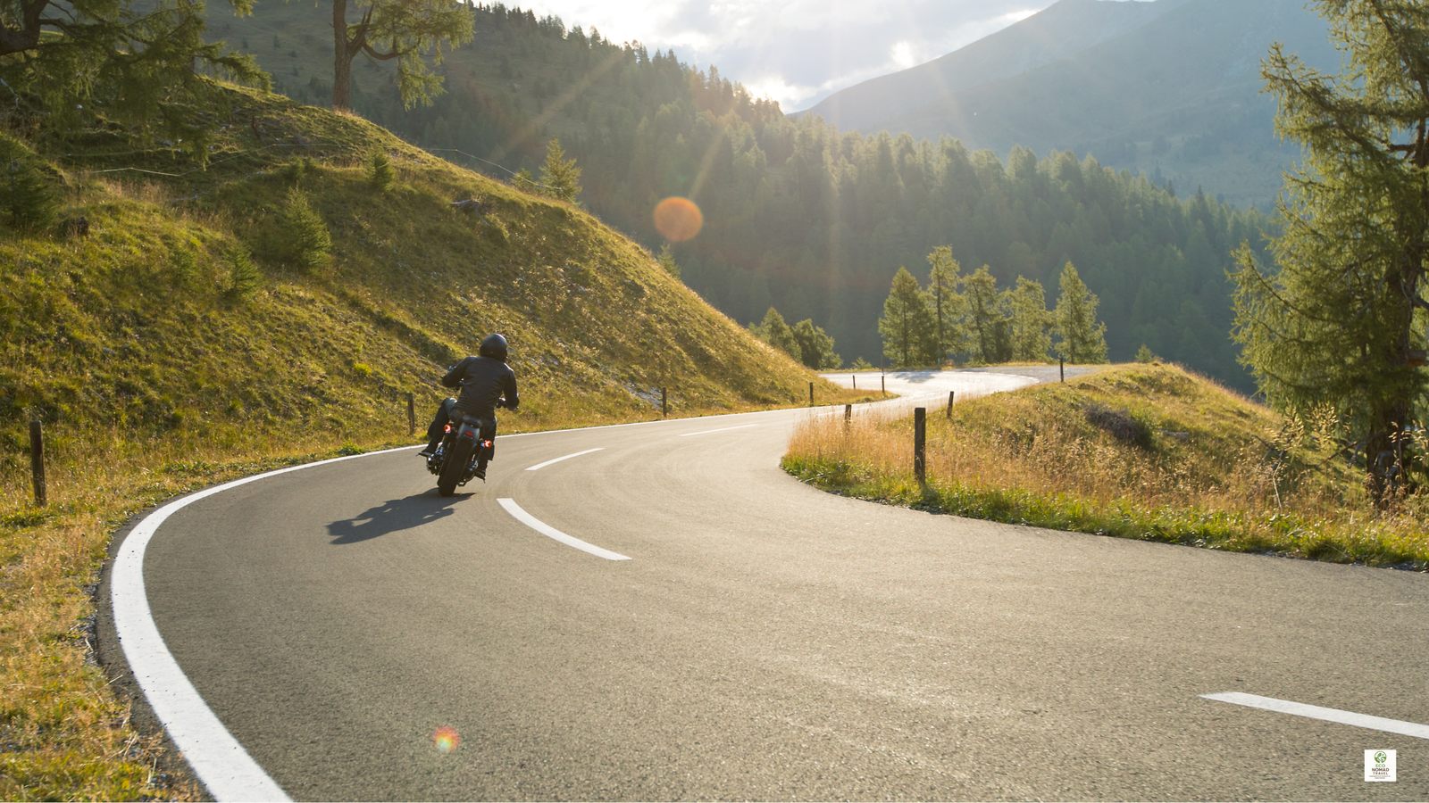 Motorbike rider on a winding mountain road in the Austrian Alps during a scenic sustainable road trip vacation