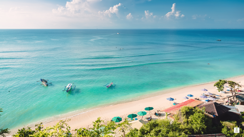 Bali island of Indonesia beach with soft golden sand and clear blue water under a bright tropical sky.