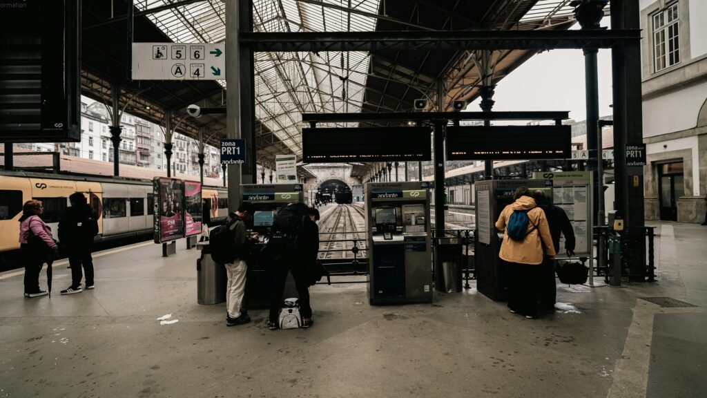 Travelers at European train station ticket machines while planning train travel costs