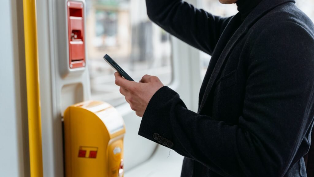 Traveler using a smartphone while riding a train (booking-app context for Omio vs Trainline)