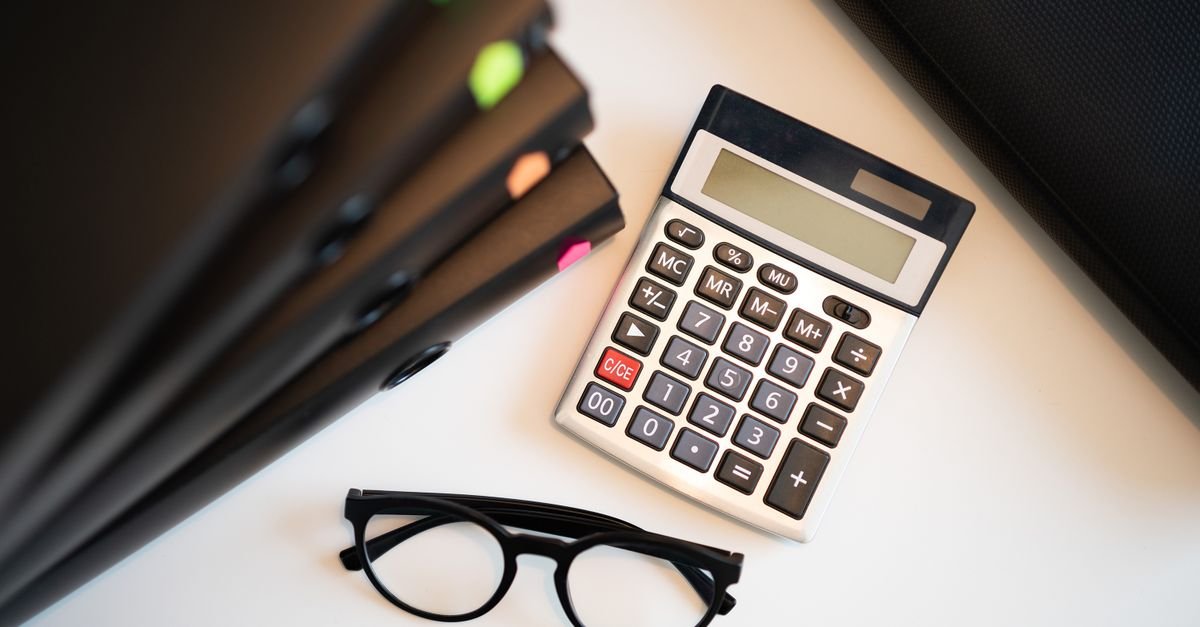 A passport and paperwork beside a calculator