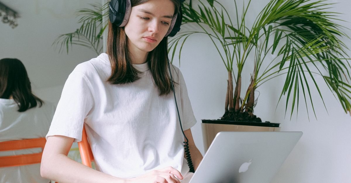 Someone wearing headphones and working on a laptop while travelling